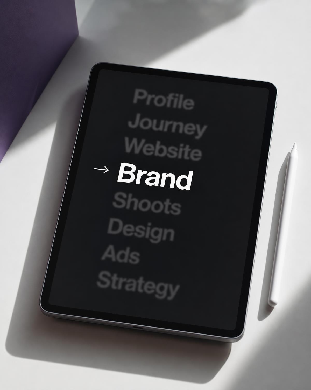 Tablet and stylus on a light surface showing a brand strategy list with Brand highlighted